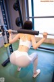 A woman squatting with a barbell in a gym.