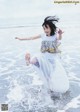 A young girl is jumping in the water at the beach.