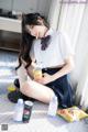 A woman in a school uniform sitting on the floor eating food.