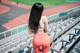 A woman in a sports bra top and leggings standing in a stadium.