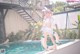 A woman in a bikini standing next to a swimming pool.