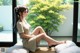 A woman sitting on a bean bag chair in front of a window.