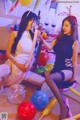 Two young women sitting on the floor surrounded by balloons.