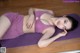 A woman laying on a purple yoga mat on the floor.