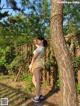 A woman standing next to a tree in a yard.