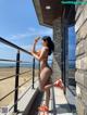 A woman in an orange bikini standing on a balcony.