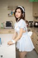 A woman in a blue dress standing in a kitchen.