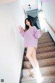 A woman in a purple sweater is standing on some stairs.