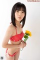 A woman in a red and white striped bikini holding a sunflower.