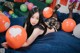 A woman laying on a bed with a bunch of balloons.