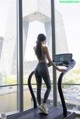 A woman is running on a treadmill in a gym.