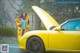 A woman standing next to a yellow sports car.