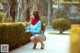 A woman in a blue sweater and red shoes crouching down on a sidewalk.