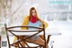 A woman sitting at a table in the snow.