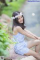 A woman sitting on a rock with a flower crown on her head.