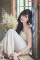 A woman in a white dress sitting on a window sill.