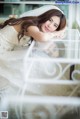 A woman in a wedding dress laying on a glass table.