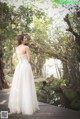 A woman in a wedding dress standing on a wooden bridge.