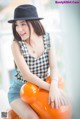 A woman sitting on top of an orange teddy bear.