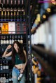 A woman standing in front of a wall of bottles of wine.