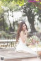 A woman in a wedding dress sitting on a bench.