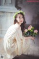 A woman in a white dress holding a bouquet of flowers.