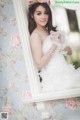 A woman in a wedding dress sitting on a window sill.