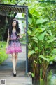 A woman in a pink dress standing on a wooden walkway.