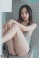 A woman sitting on top of a kitchen counter next to a sink.