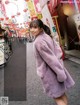 A woman in a purple coat is walking down the street.