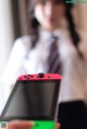 A woman in a white shirt and tie holding a red Nintendo Switch.