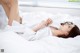 A woman laying on a bed in a white shirt.