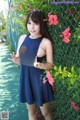 A woman in a blue dress posing in front of a fence.