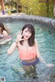 A woman in a pink top and blue bikini in a pool.