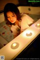 A woman in a bathtub with candles on the edge of it.