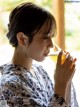 A woman in a kimono drinking from a glass.