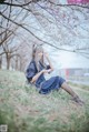 A woman in a blue dress sitting in the grass.