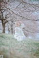 A woman in a white dress sitting under a tree.