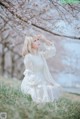 A woman in a white dress sitting under a tree.