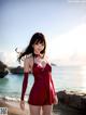 A woman in a red bathing suit standing on a beach.