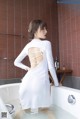 A woman in a white dress standing in a bathtub.