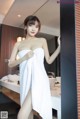 A woman in a white towel standing in front of a mirror.