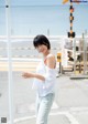 A woman standing on the side of a road next to the ocean.