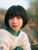 A young woman wearing a white sweater and a green scarf.