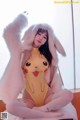 A woman in a Pikachu costume sitting on a bed.